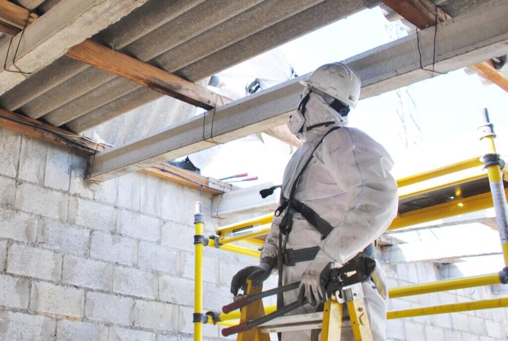 A professional dismantles a fiber cement roof as part of an asbestos assessment and removal.